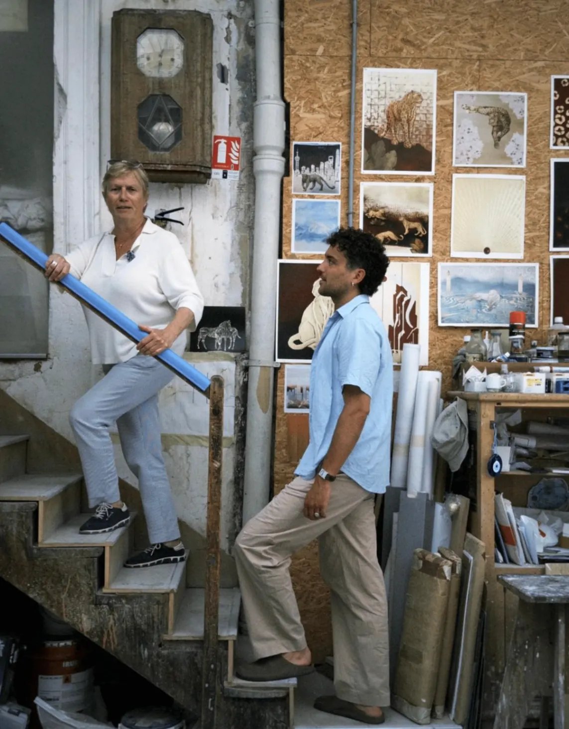 Échange dans un atelier d'art devant un mur d'œuvres et de maquettes